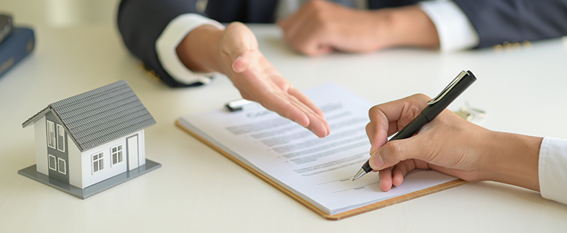 Consórcio ou financiamento - Corretores com casa em miniatura na mesa