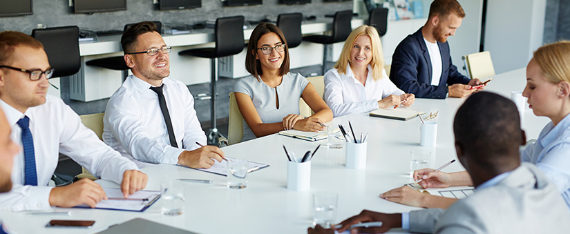Gestão de vendas: grupo de colaboradores conversa sorridente ao redor da mesa