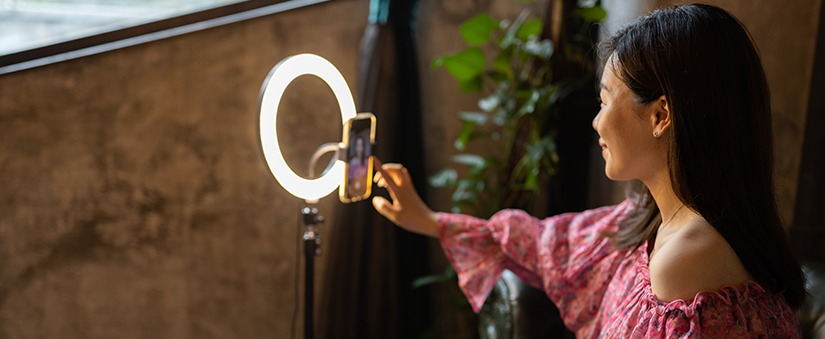 Instagram: mulher grava vídeo através da câmera frontal do celular. Atrás do celular, um ring light pode ser visto