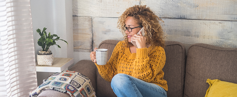 Pós-venda para corretores: mulher sorridente fala ao celular e segura xícara de café