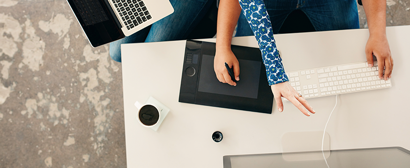 Tendências de consumo: uma mão utiliza mesa digitalizadora enquanto digita no teclado do computador