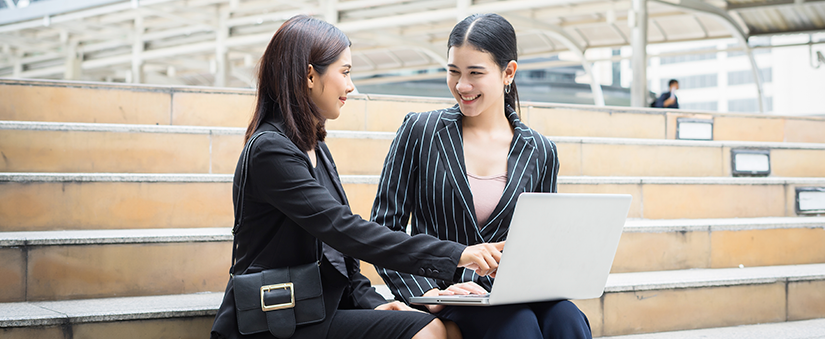 Tendências de consumo: corretora e cliente sorriem enquanto conversam e apontam para o computador