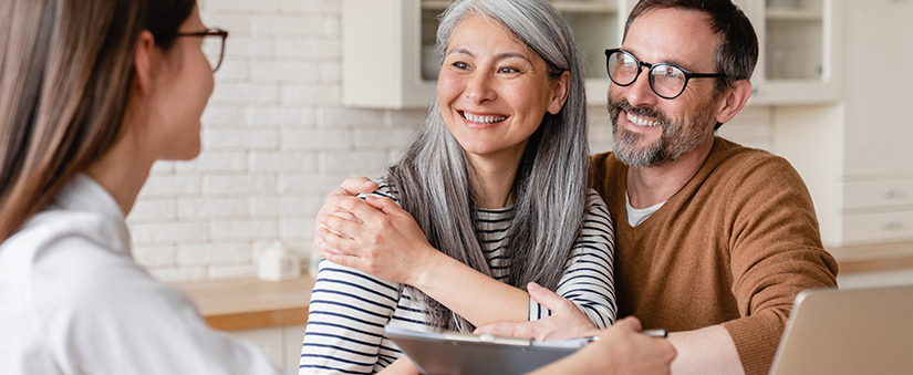 Casal se abraça enquanto conversa com corretora de imóveis
