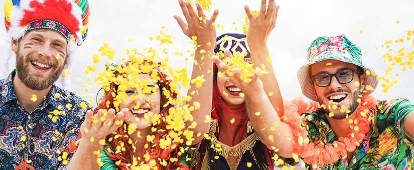 Pessoas felizes e fantasiadas jogando confete para o alto