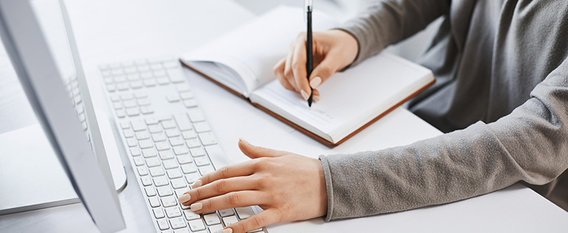 Storytelling: pessoa escreve num caderno enquanto digita num teclado de computador.