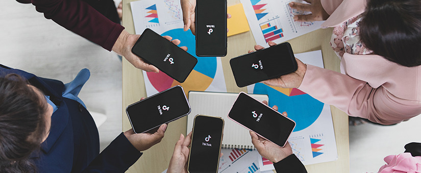 Câmera superior: seis celulares com telas escuras e a marca do tiktok