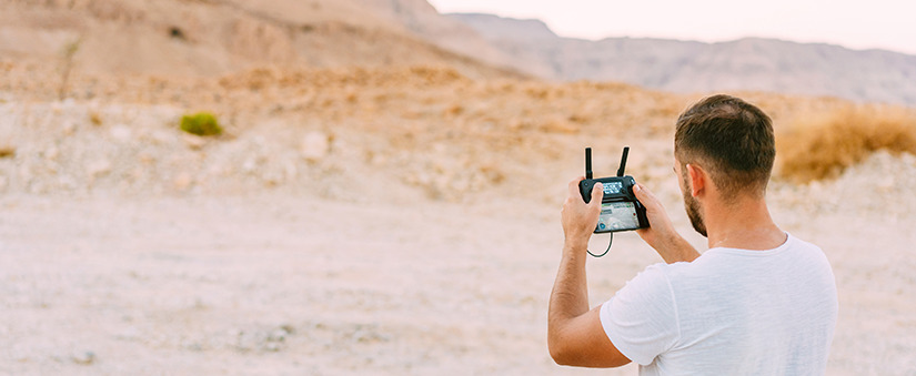 Drones: homem controla drone em terreno