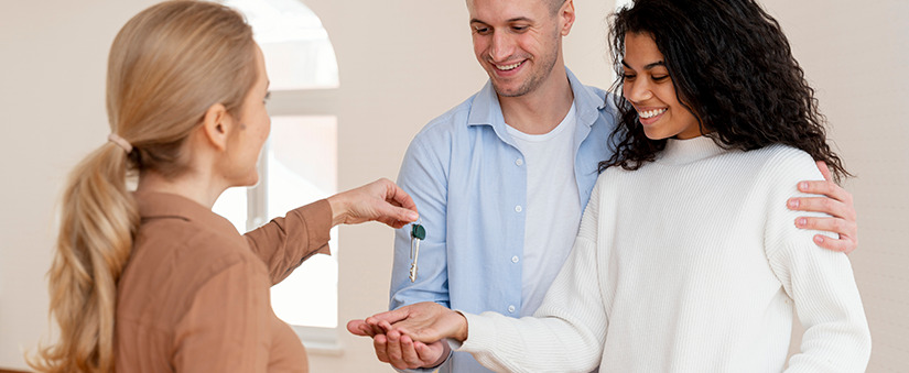 corretor de imóveis entregando a um casal sorridente as chaves de sua nova casa como resultado de estratégias de Spin Selling