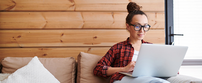 venda de imóveis mulher sentada num sofá com um notebook no colo.
