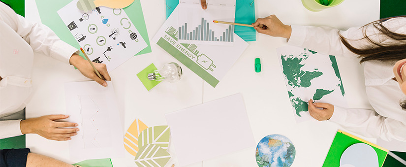 práticas sustentáveis: mesa vista de cima com vários papeis e símbolos que representam sustentabilidade