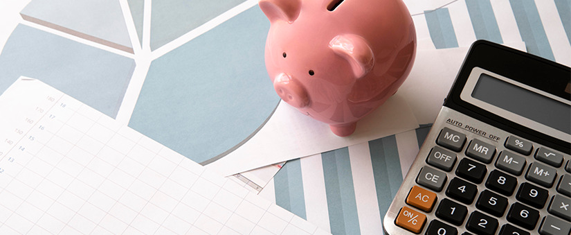 como ser bem-sucedido no mercado imobiliário como virar corretor de imóveis: imagem de uma mesa com papeis, uma calculadora e um cofre em formato de porco.