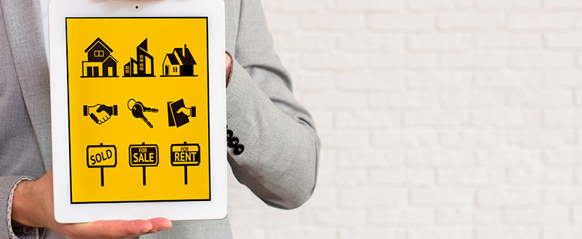 gestão para incorporadoras ferramentas de gestão: pessoa segurando um tablet com ícones na tela de casas, chaves, apartamentos e placas de "vende-se".