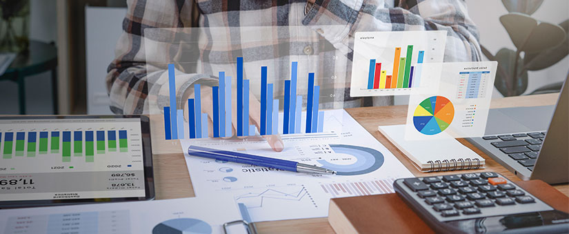 gestão orientada a dados mesa com muitos papeis com gráficos, notebook, calculadora e, acima, hologramas de gráficos.