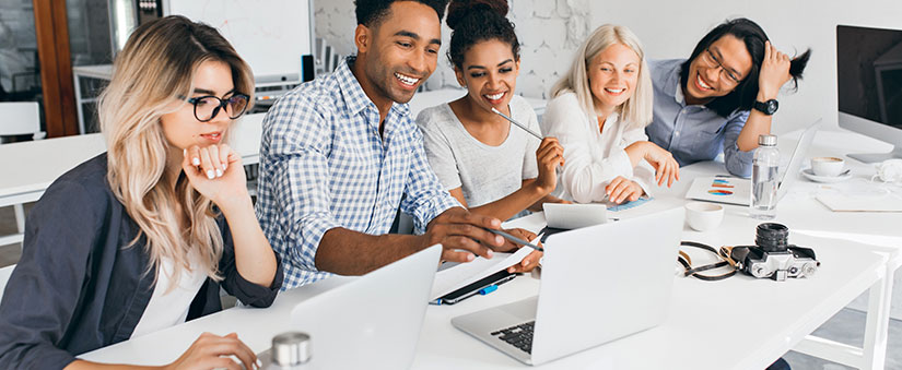 anonimização de dados anonimização de dados: grupo de pessoas sorrindo à frente de uma mesa com um notebook e alguns papeis.