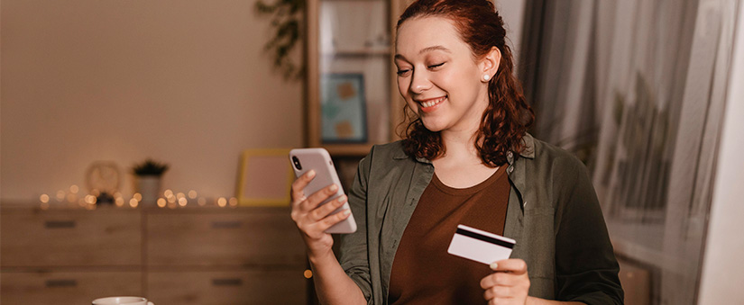 pagadoria pagadoria: mulher segurando um cartão com uma mão e um celular com a outra.