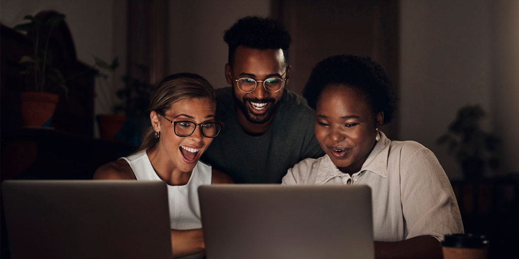 Serasa API Serasa API: trêspessoas olhando para um notebook com expressões de surpresa e felicidade.