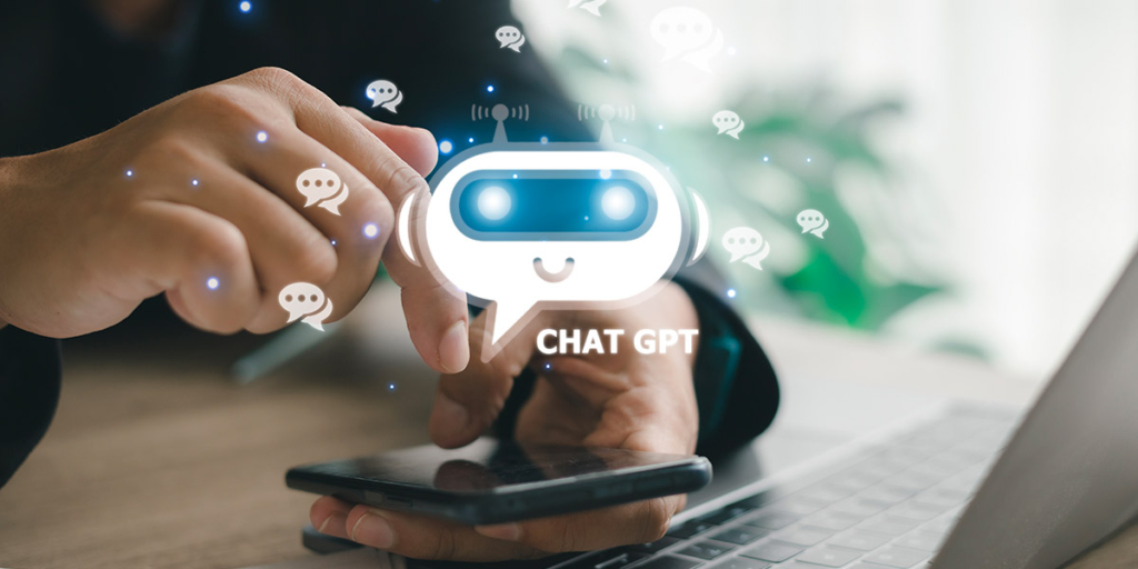 chat gpt close em mãos segurando um celular ao lado de um notebook. Accima do celular um ícone do chat.