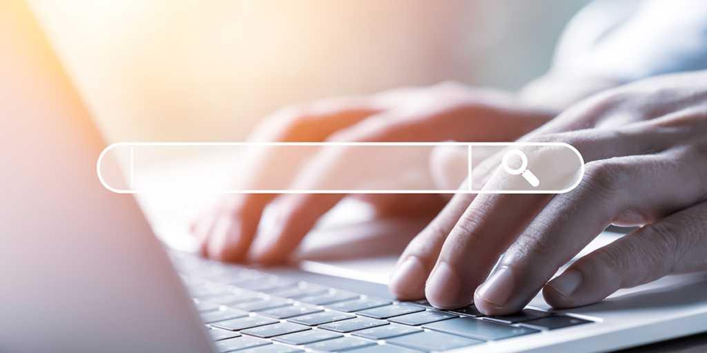 Site de imóveis Site de imóveis: close em mãos num teclado de notebook. À frente uma caixa de busca.