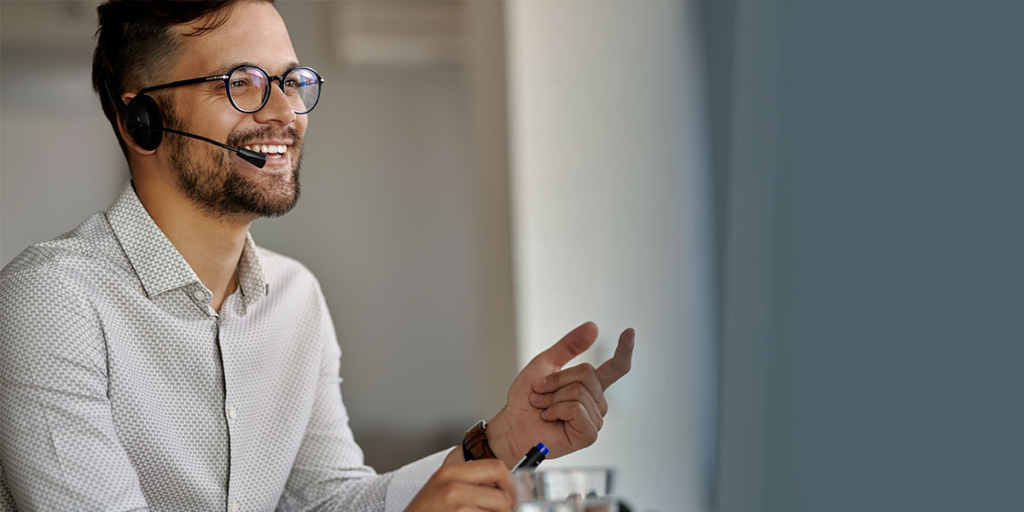 captar leads captar leads: imagem de um homem falando num microfone de fone e sorrindo.