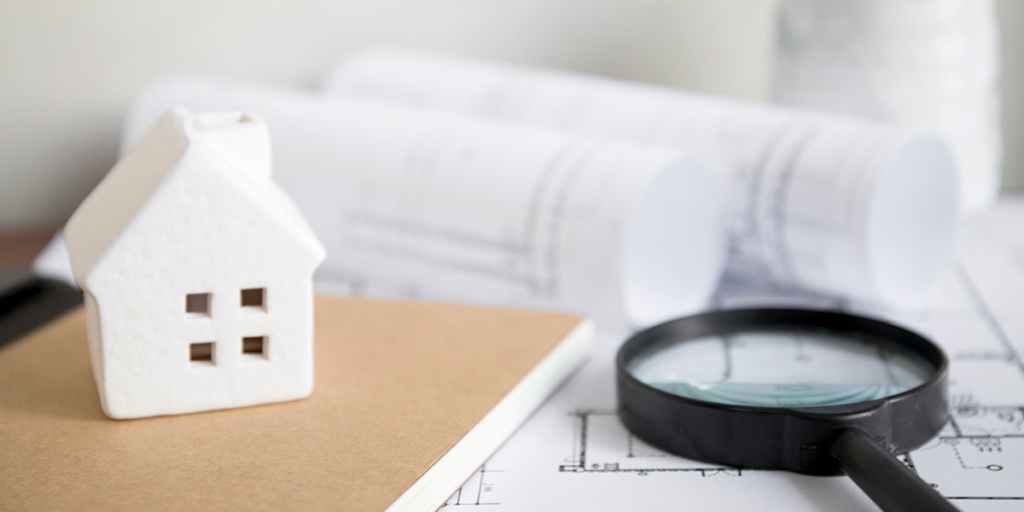 vistoria de apartamento novo vistoria de apartamento novo: imagem de uma miniatura de casa numa mesa ao lado de uma lupa.