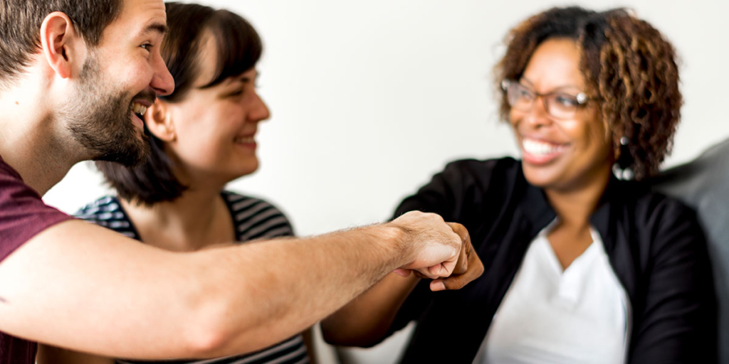 O que é Rapport em vendas O que é Rapport em vendas: imagem de um casal sorridente cumprimentando uma mulher.