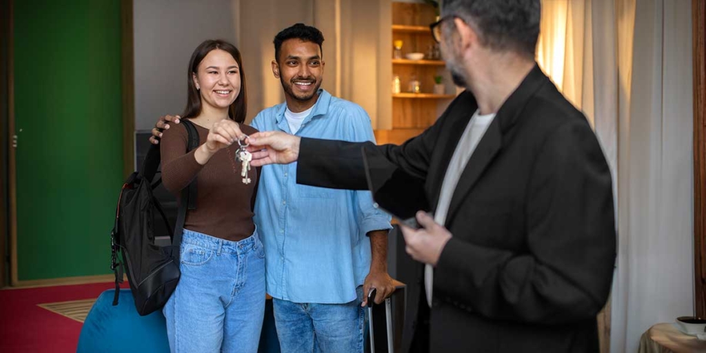 compra de imóveis: homem entregando uma chave a um casal.