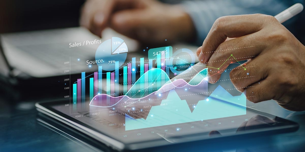 KPI’s de vendas KPI’s de vendas: close numa mão usando uma caneta digital num tablet. À frente da imagem alguns gráficos em transparência.