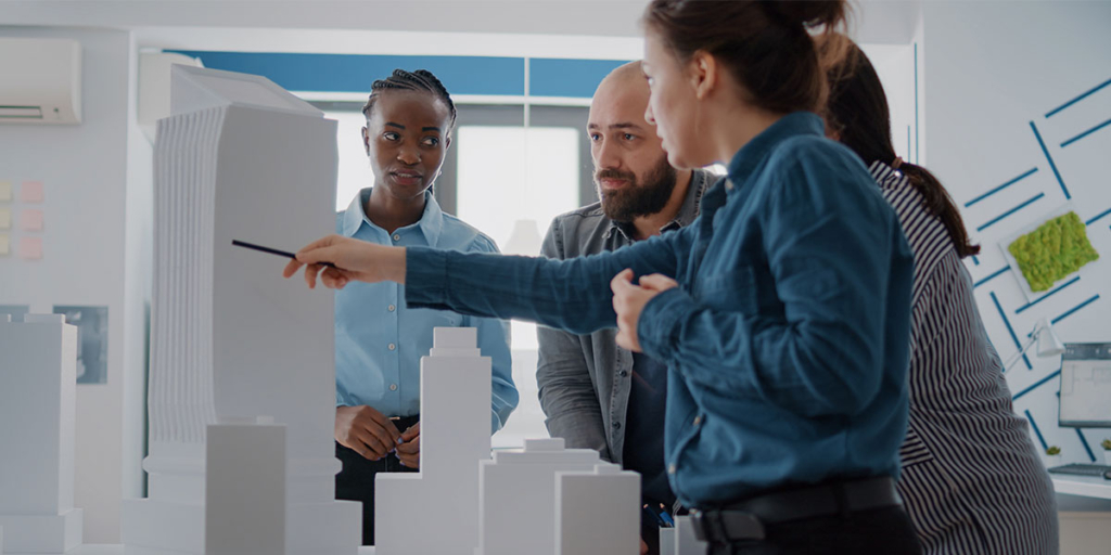 O que é eap O que é eap: imagem de quatro pessoas olhando e analisando uma maquete com alguns edifícios,