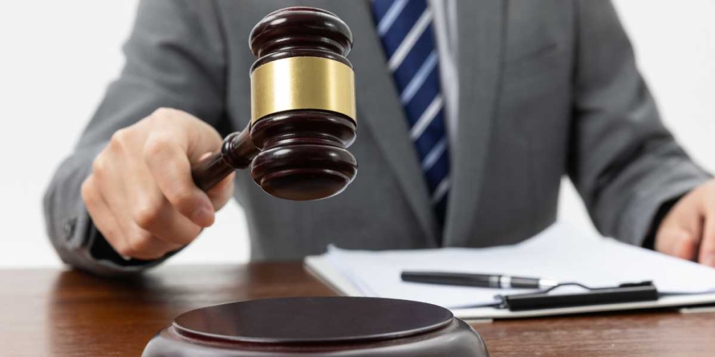 Registro de Incorporação Imobiliária: close na mão de uma pessoa de terno segurando um malhete.