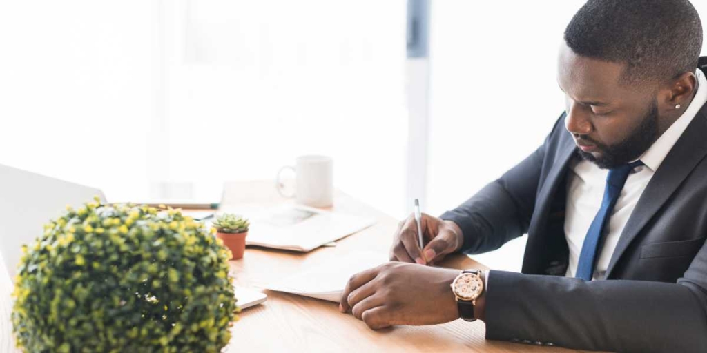 Registro de Incorporação Imobiliária: homem de terno, sentado à frente de uma mesa assinando um papel.
