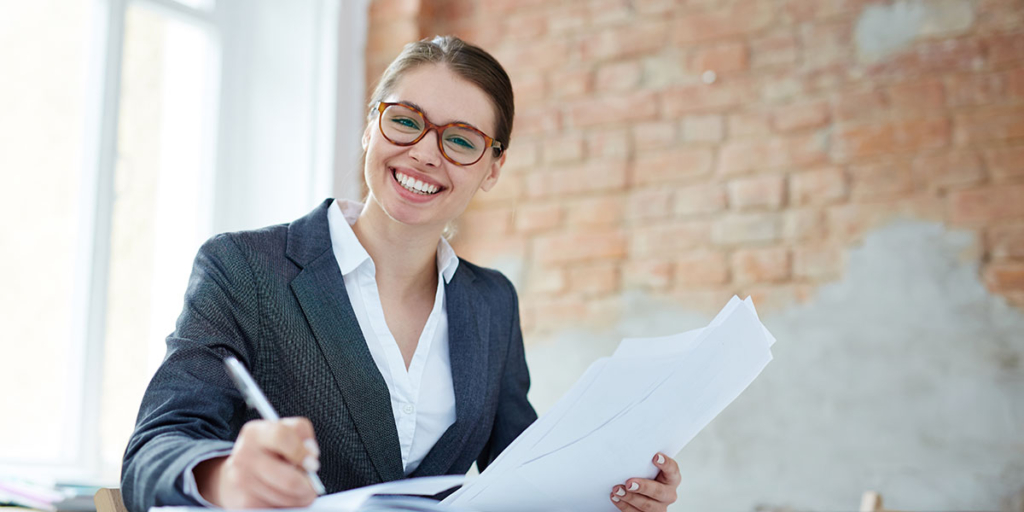 Burocracia Administrativa Burocracia Administrativa: imagem de uma mulher assinando papeis e sorrindo.