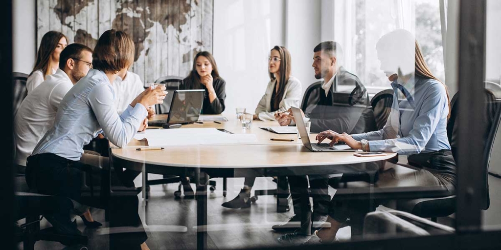 Experiência com CRM Experiência com CRM: sala de reunião com várias pessoas em volta de uma mesa.