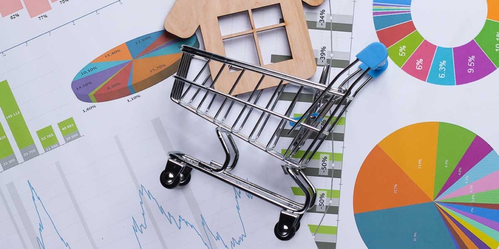 O que é INCC O que é INCC: imagem de um carrinho de compras em miniatura em cima de alguns papeis com gráficos coloridos