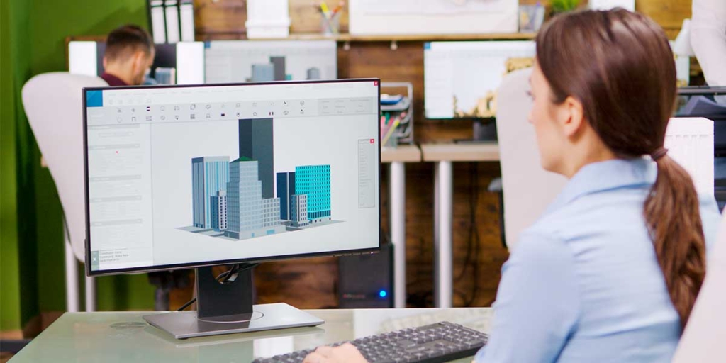 Software para pequenas construtoras Software para pequenas construtoras: imagem de um escritório com vários computadores. Em destaque, uma mulher de costas e, na tela do computador à frente dela, ilustração de alguns prédios.