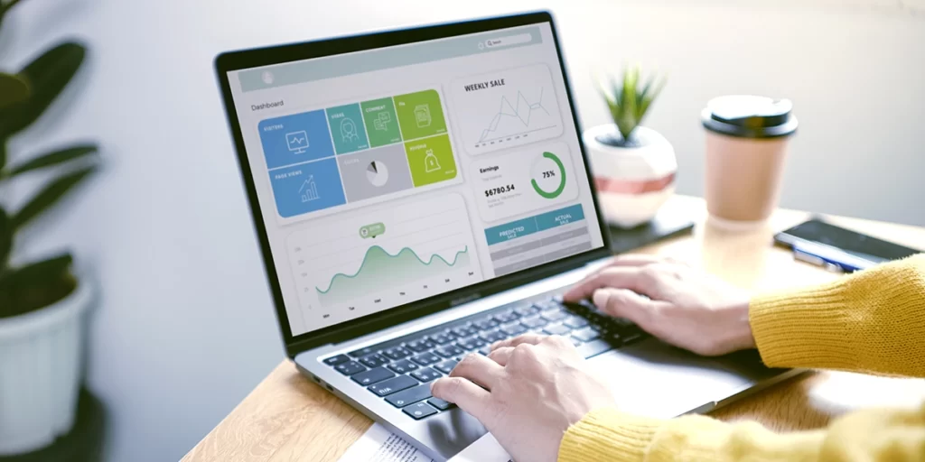 CRM Analítico CRM Analítico: imagem de mãos de uma pessoa num notebook. Na tela, um dashboard com alguns dados.