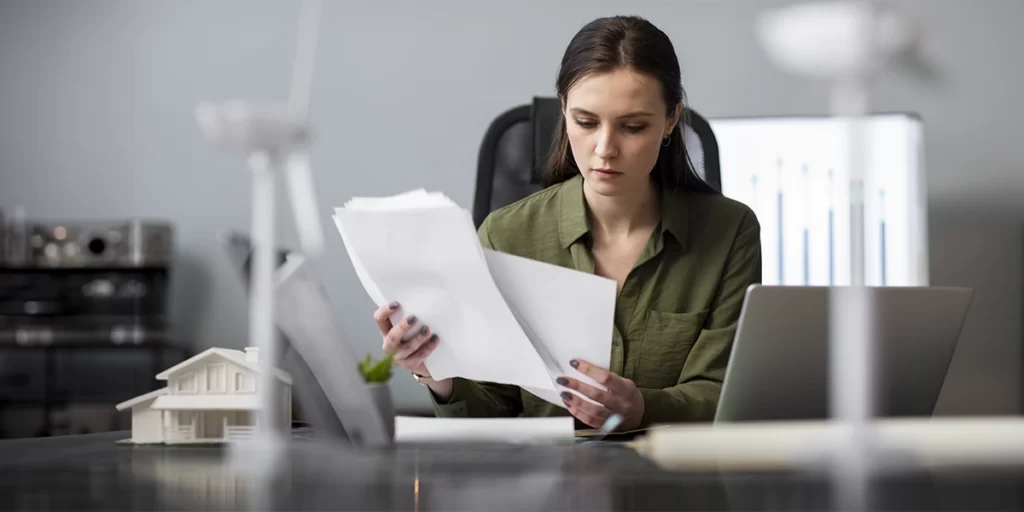 Gestor Imobiliário Gestor Imobiliário: imagem de uma mulher em frente a uma mesa segurando alguns papeis