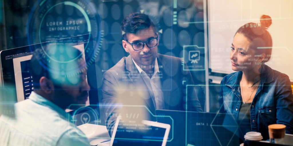 Sistema Imobiliário Sistema Imobiliário: imagem de três pessoas em frente a um computador. Ela se olham entre si.