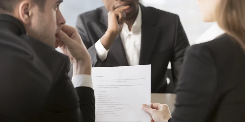 Distrato ou rescisão Distrato ou rescisão: três pessoas conversando. Uma delas segura um papel, que está em foco na imagem.