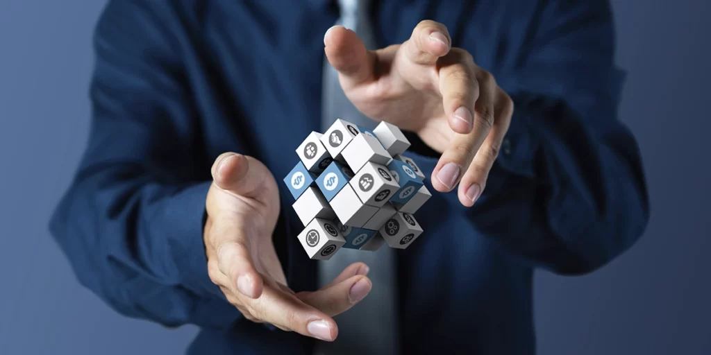 NIRF NIRF: close nas mãos de uma pessoa focando num bloco que flutuam. Cada quadrado do bloco tem um ícone relacionado a gráficos, tempo, dinheiro, etc.