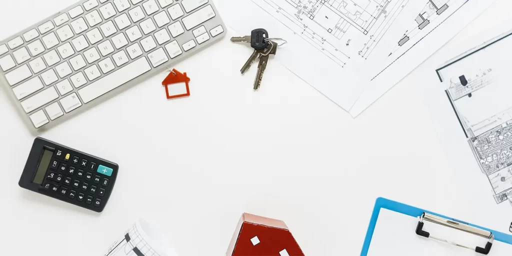 Negócios imobiliários Negócios imobiliários: imagem de uma mesa vista de cima com alguns papeis, chaves, um teclado de computador, uma calculadora.