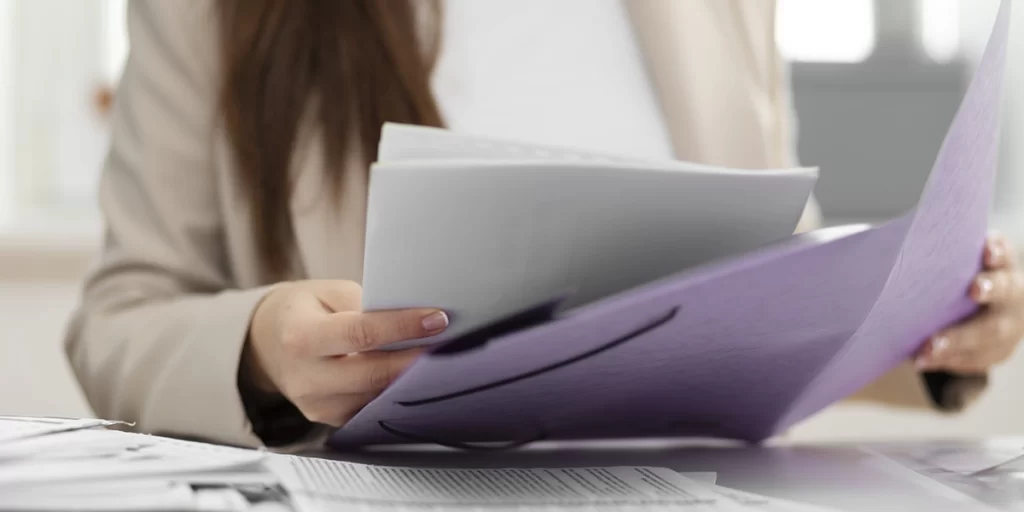 RRT RRT: close nas mãos de uma mulher segurando vários papeis.