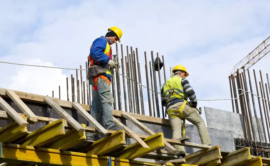 NR 17 NR 17: imagem de um canteiro de obras e dois homens trabalhando numa estrutura alta.