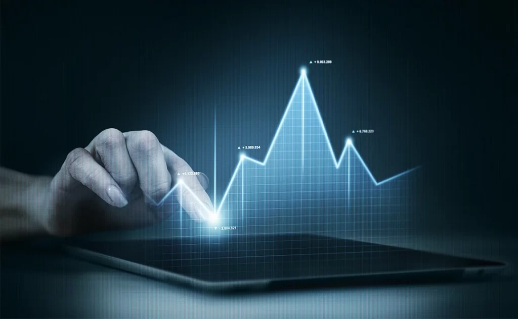 vantagens da inteligência artificial vantagens da inteligência artificial: imagem de uma mão apontando para um tablet numa mesa. Acima da tela sai um gráfico de linha.