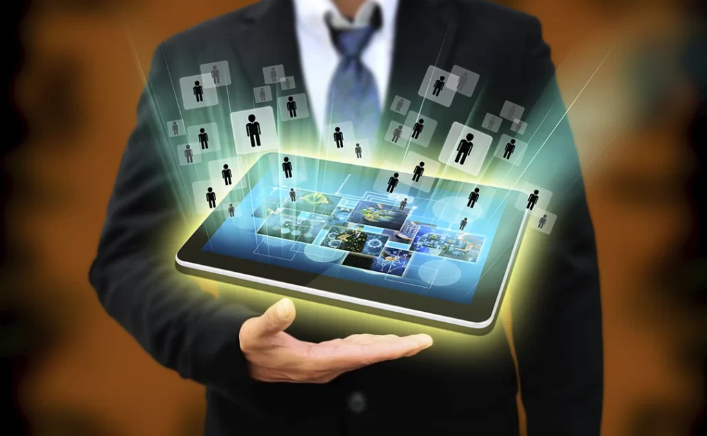 CRM imobiliario gratuito CRM imobiliario gratuito: close na mão de um homem usando terno. Acima da mão, um tablet flutuando com algumas imagens na tela.