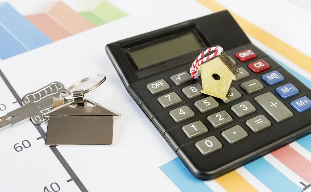 Regime especial de tributação para incorporadoras Regime especial de tributação para incorporadoras: imagem de uma calculadora em cima de alguns papeis com gráficos coloridos. Em cima da calculadora a miniatura de uma casa de madeira.