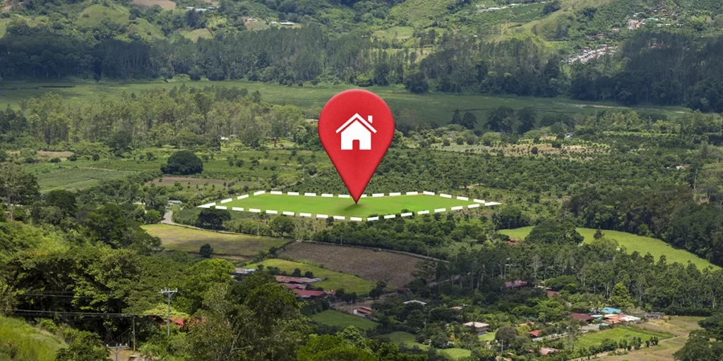 compra de lotes compra de lotes: A imagem mostra um mapa com um ponto vermelho indicando a localização de uma casa no meio de uma floresta verde com montanhas no fundo. A casa está rodeada por árvores e tem uma abóbora branca. O terreno ao redor é montanhoso e coberto por vegetação.
