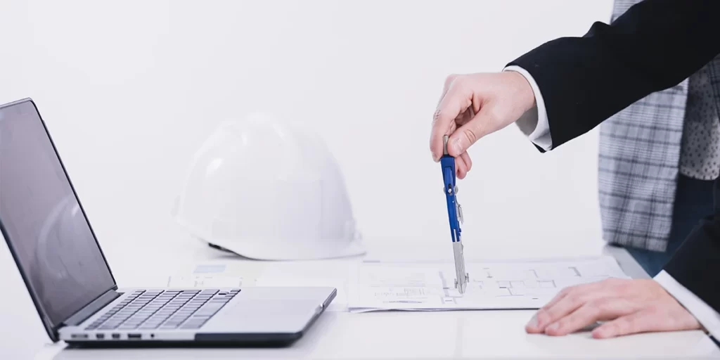 aprovação de projeto na prefeitura aprovação de projeto na prefeitura: Imagem de um homem em traje e gravata segurando uma caneta e olhando para um laptop na mesa. O laptop parece estar aberto e o homem está segurando uma folha de papel com um plano em azul. O fundo parece ser um espaço de escritório branco e azul com uma janela no fundo. A imagem está bem iluminada e as cores são vibrantes. A atmosfera geral da imagem é profissional e concentrada.