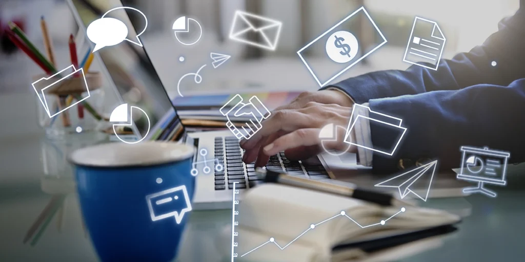 Processos automatizados no mercado imobiliário Close nas mãos de uma pessoa digitando num notebook. Em destaque na imagem vários ícones que representam processos automatizados no mercado imobiliário: