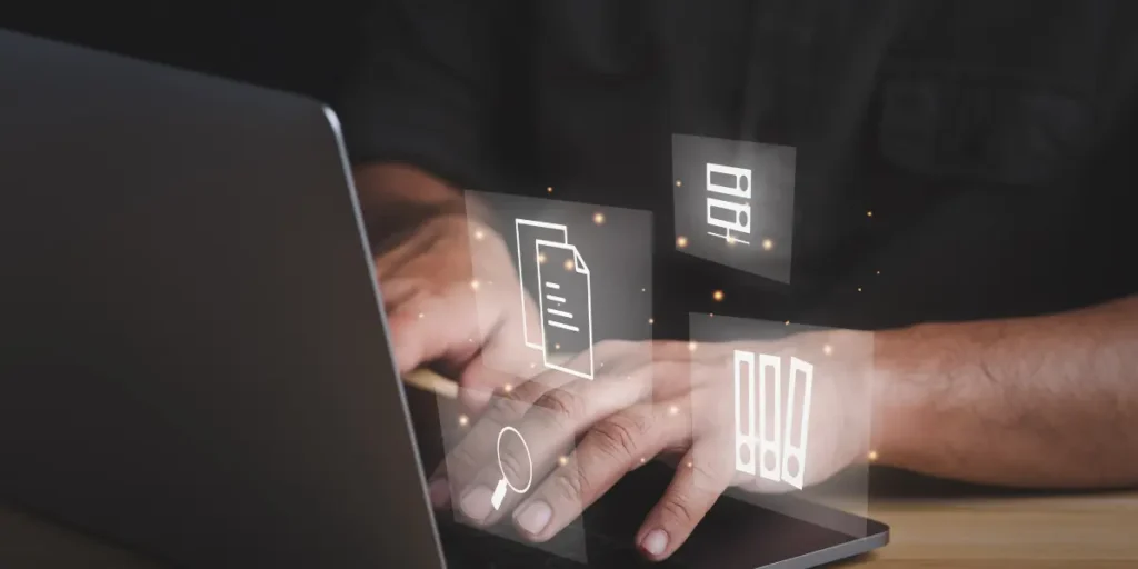 Integração de dados em incorporadoras: na imagem, uma pessoa digitando em um notebook. Na tela, vemos alguns ícones como uma lupa de pesquisa e relatórios